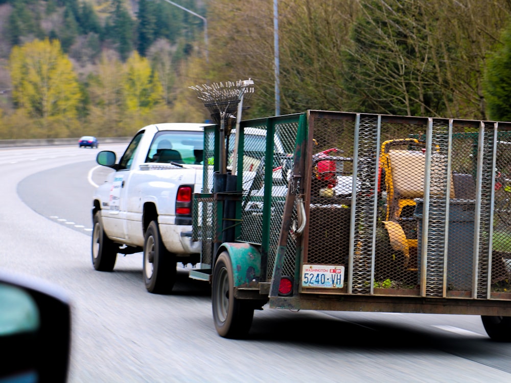 a white truck driving down a road next to a forest