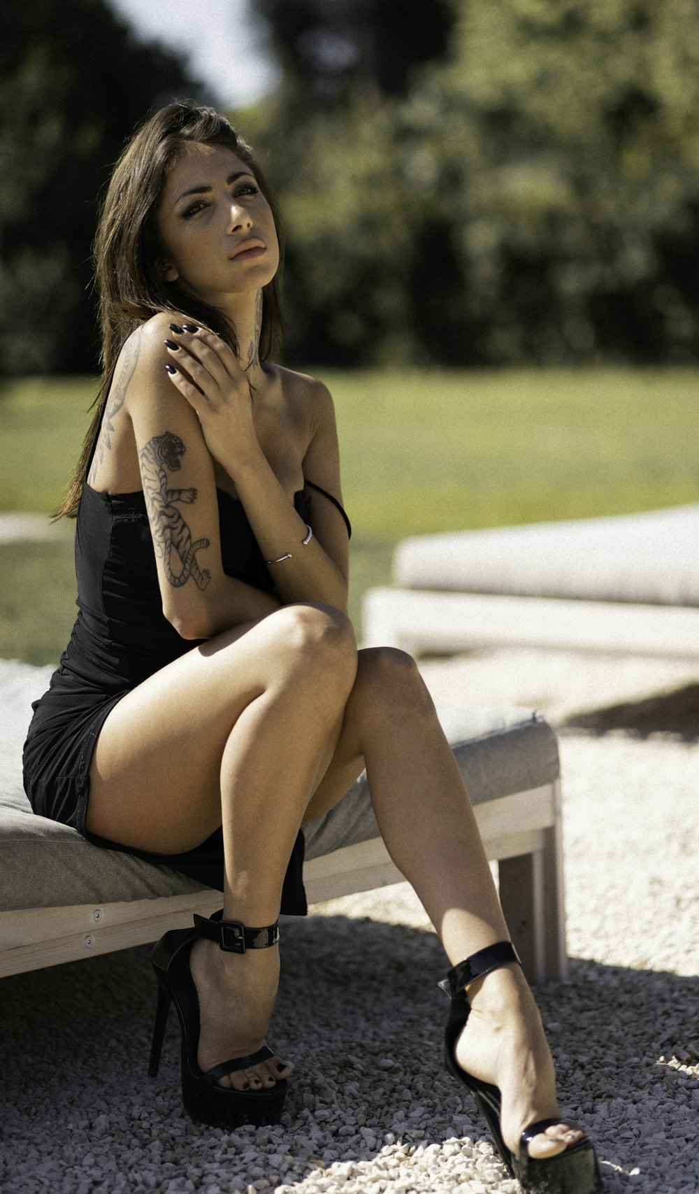 a woman sitting on a bench in a black dress