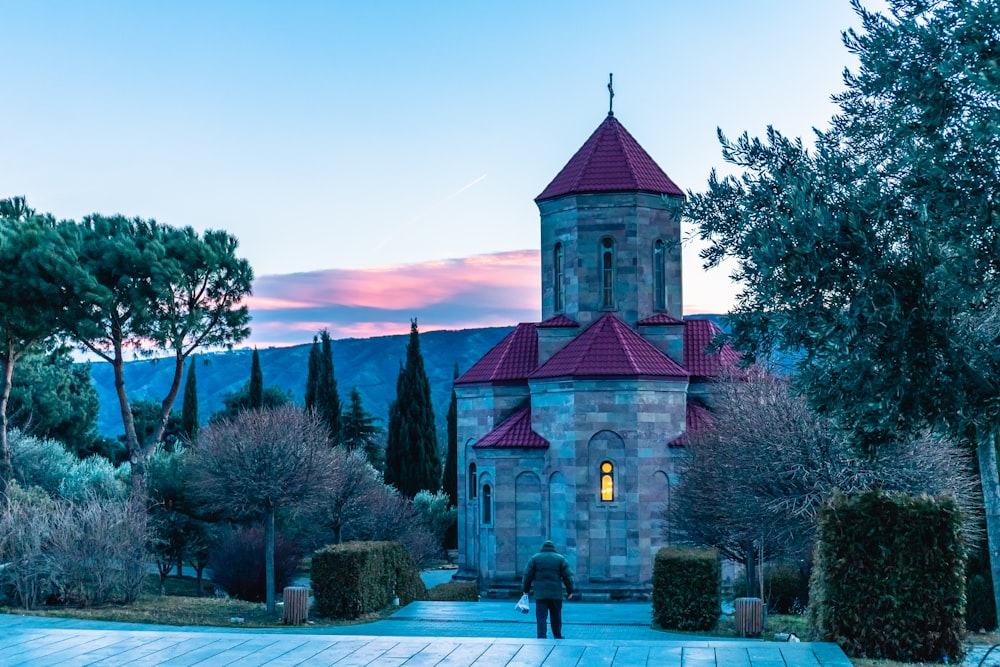 a person walking towards a church with a red roof