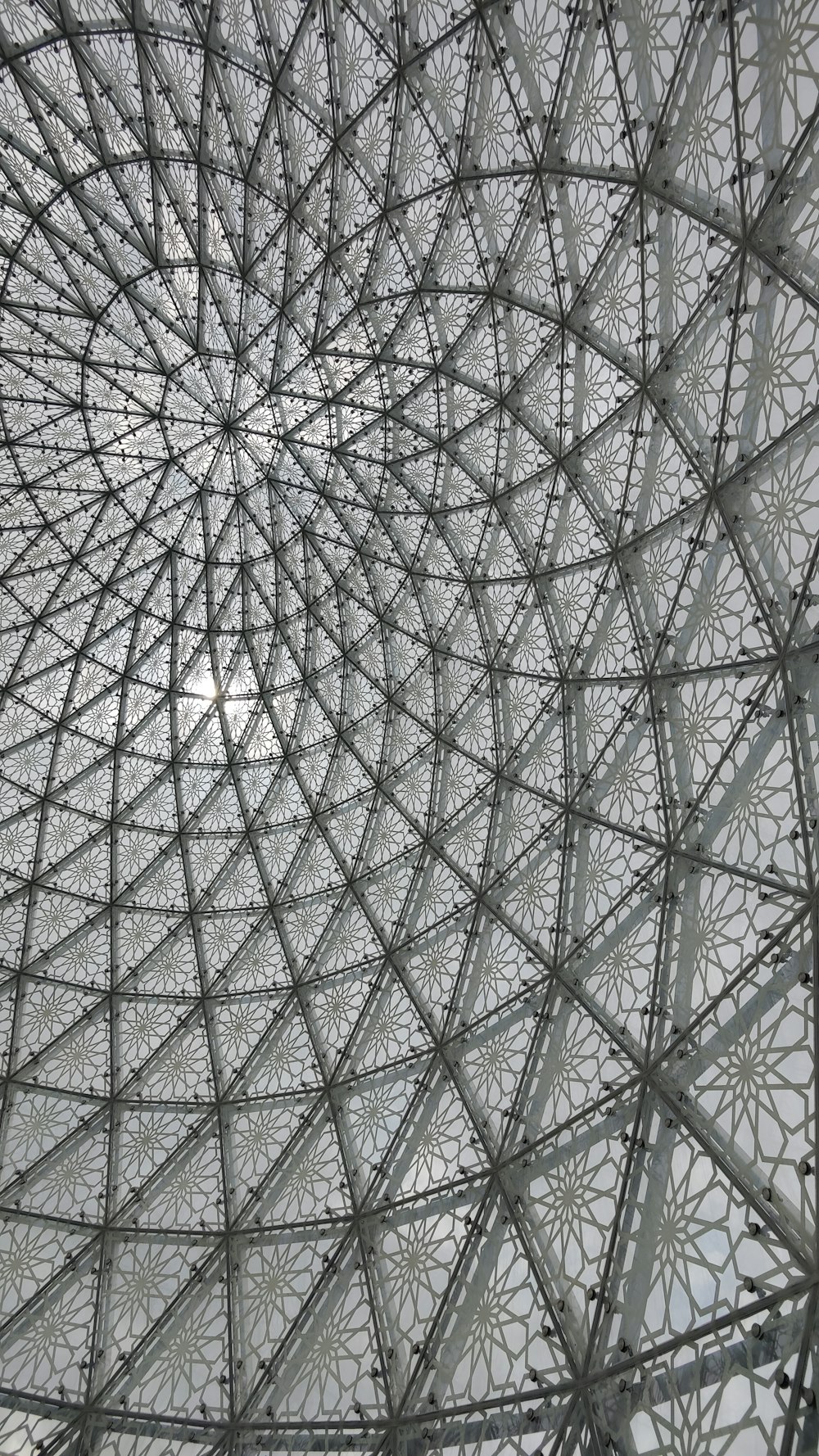 a close up of a metal structure with a sun in the background