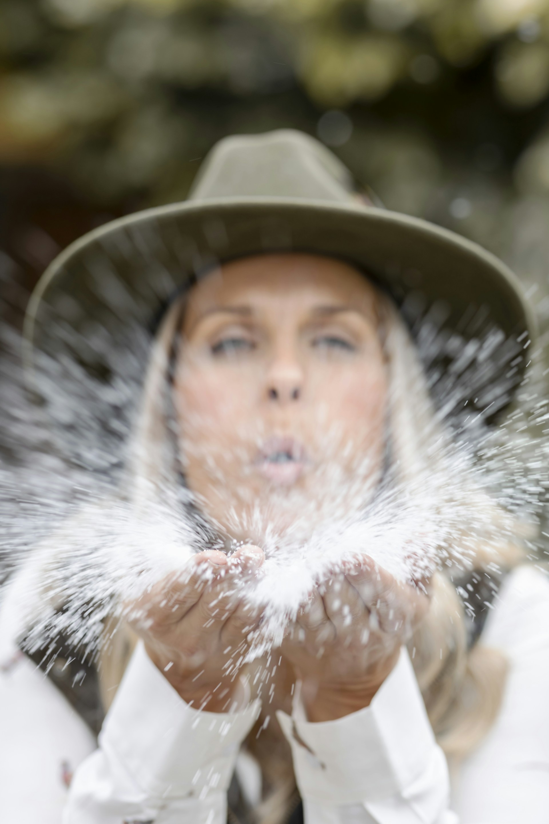 a woman in a hat is blowing snow