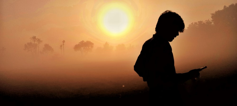 a silhouette of a person holding a cell phone