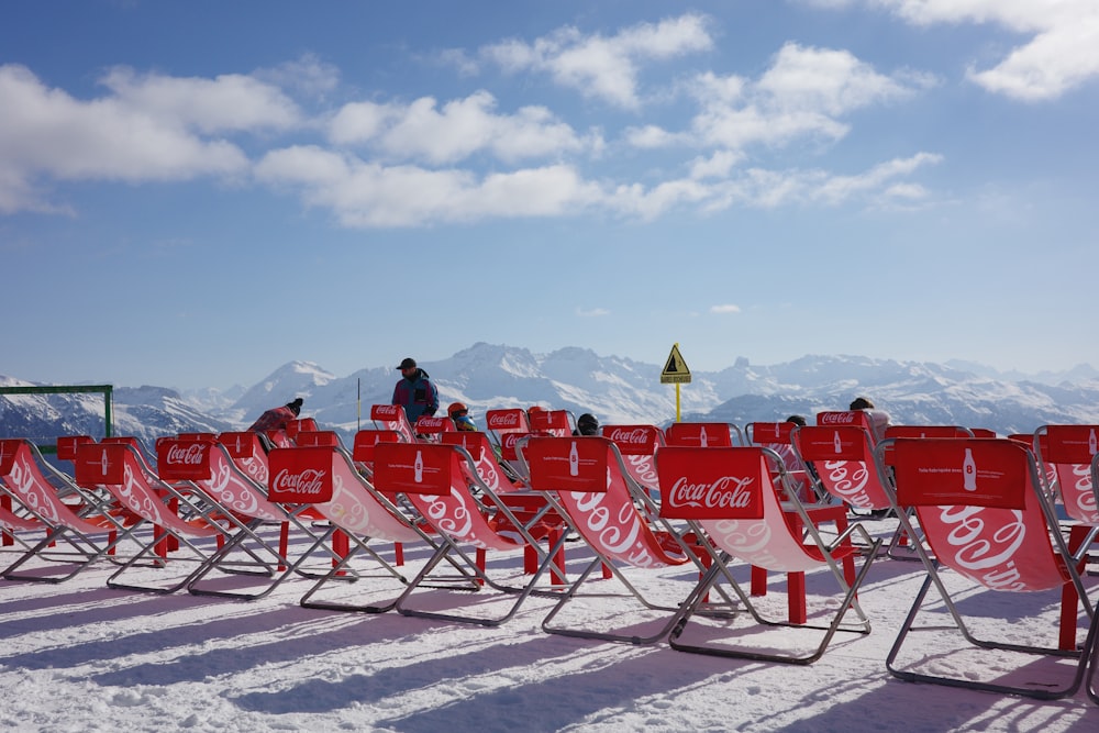 a row of red chairs sitting on top of a snow covered slope