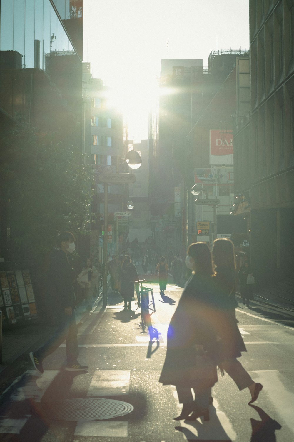 a group of people walking down a street next to tall buildings