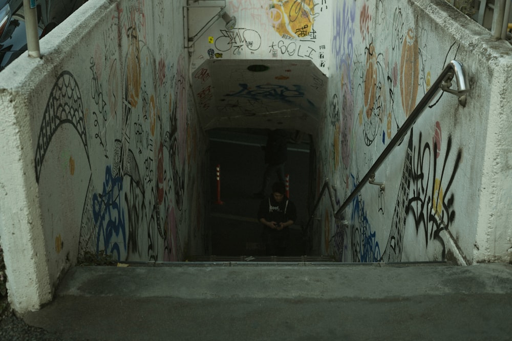 a man standing in a tunnel with graffiti all over it