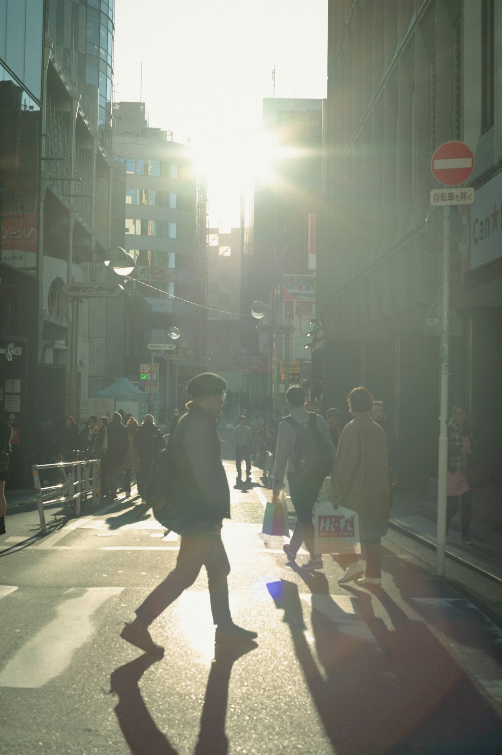 a group of people walking down a street next to tall buildings