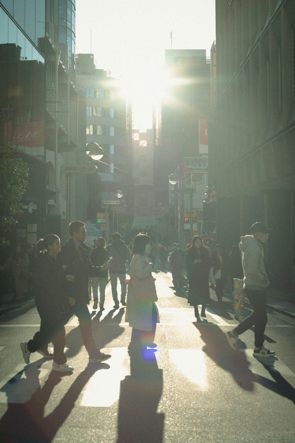 a group of people walking down a street next to tall buildings