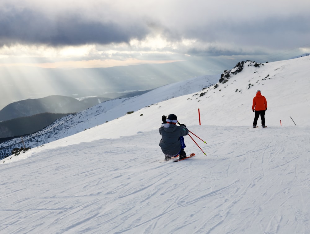 a couple of people riding skis down a snow covered slope