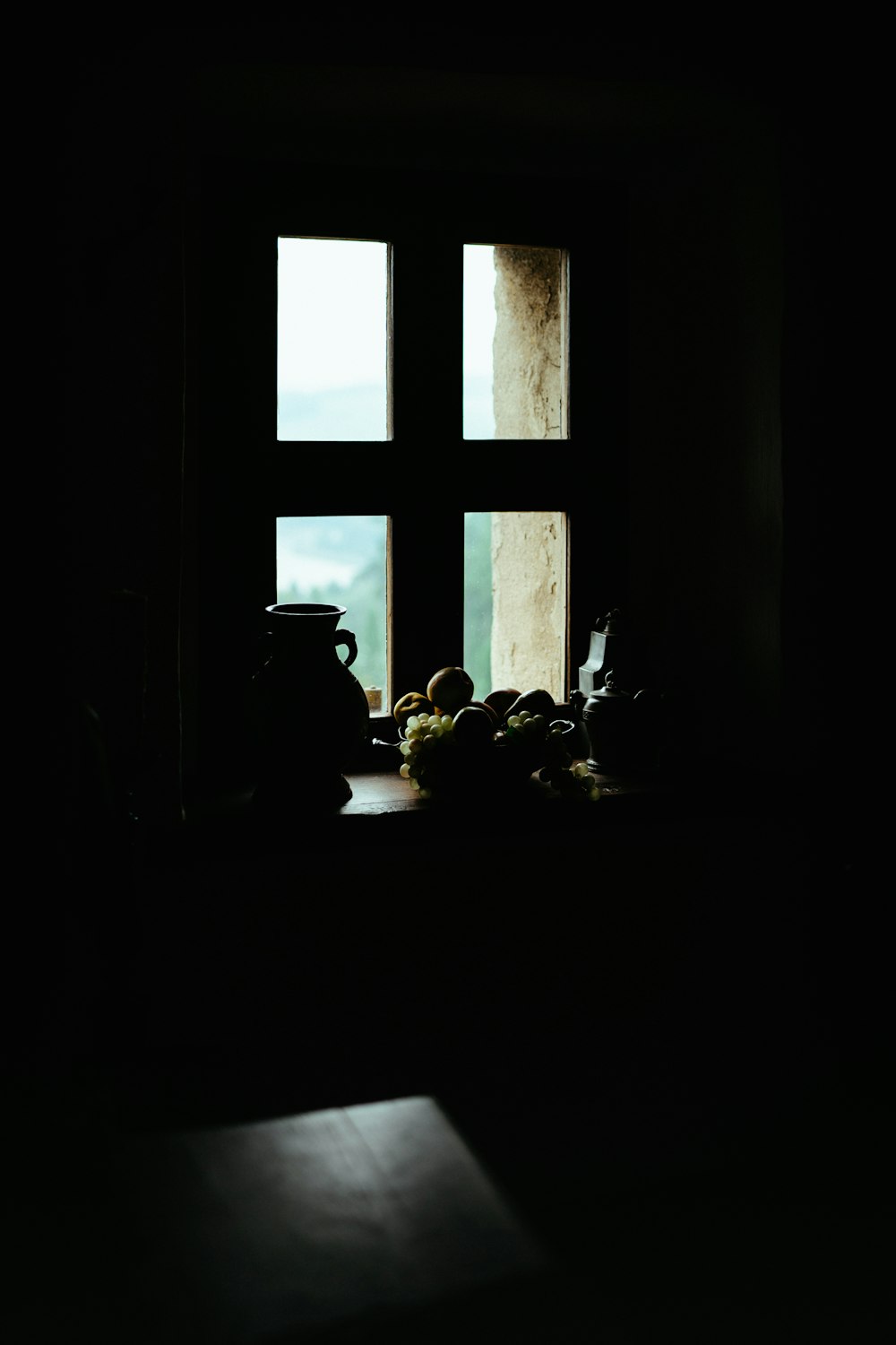 a window in a dark room with a bowl of fruit