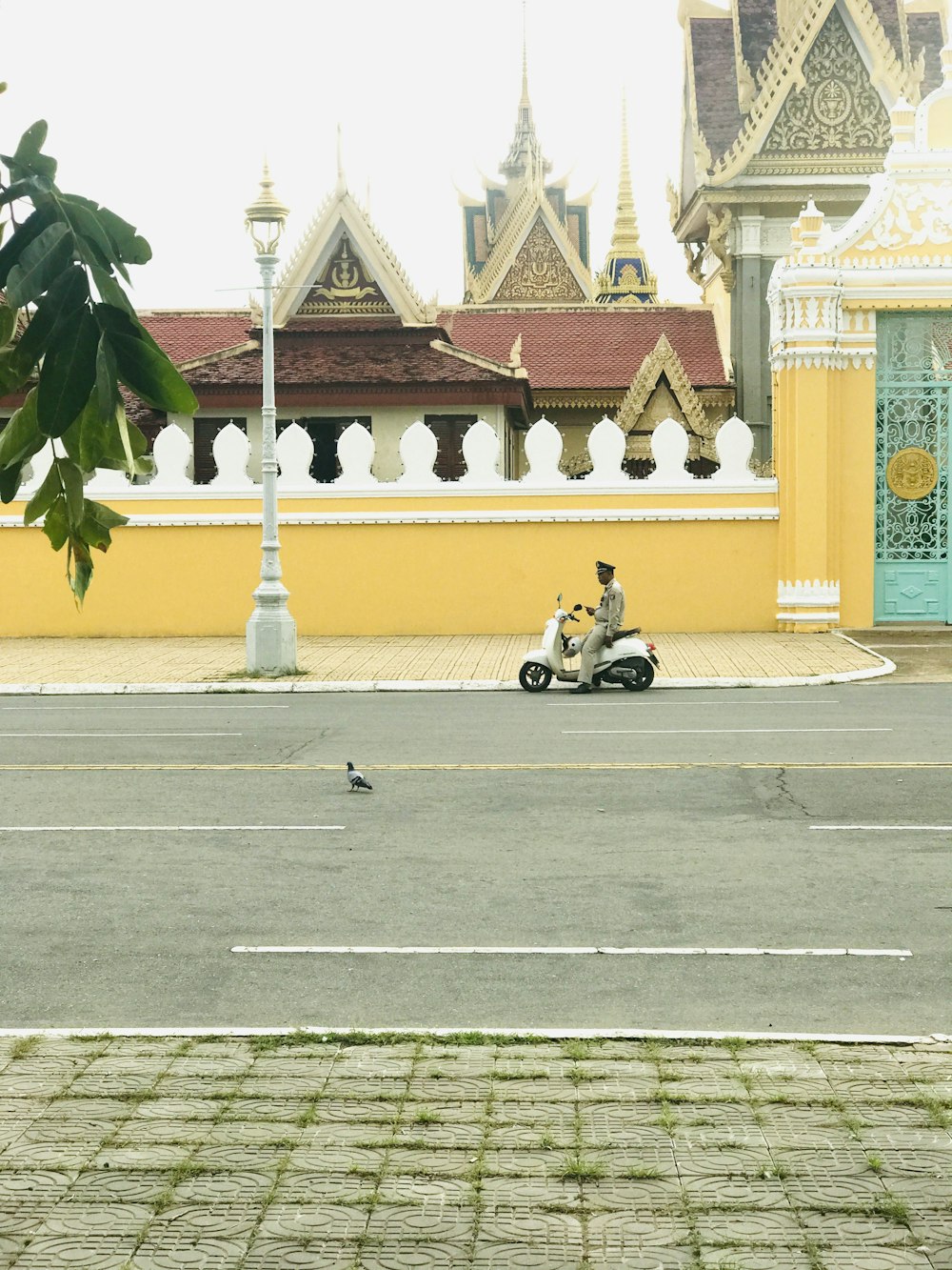 a man riding a scooter down a street next to a yellow building