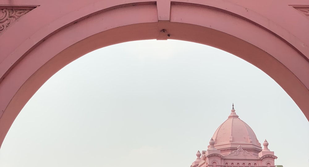 a view of a pink building through an archway