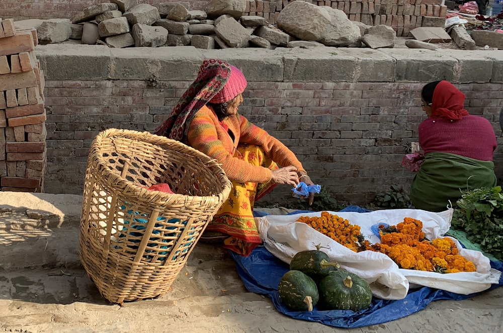a woman sitting on the ground next to a basket of food