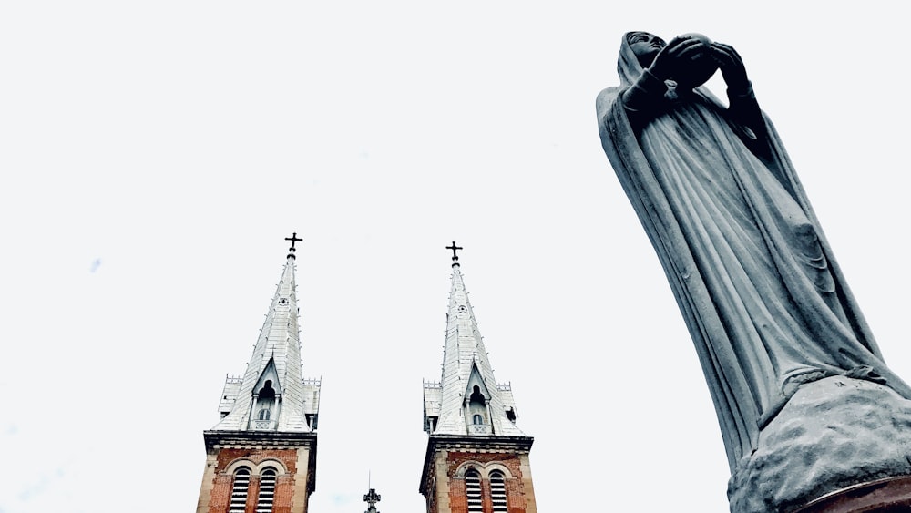 a statue of a person with their hand up in front of a church steeple