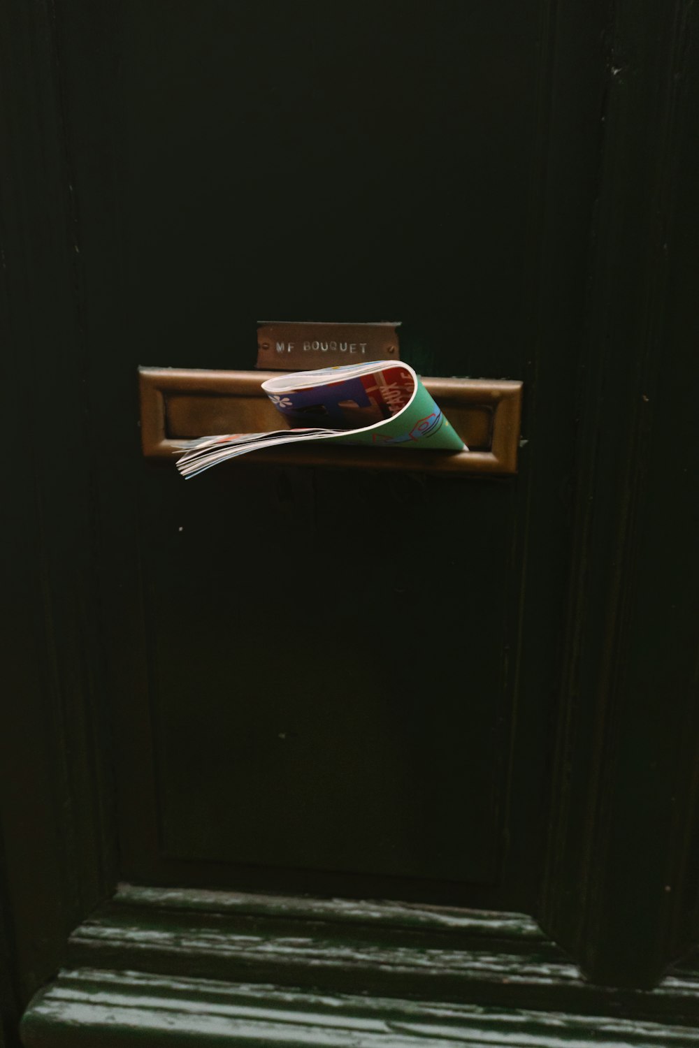 a green door with a newspaper holder on it
