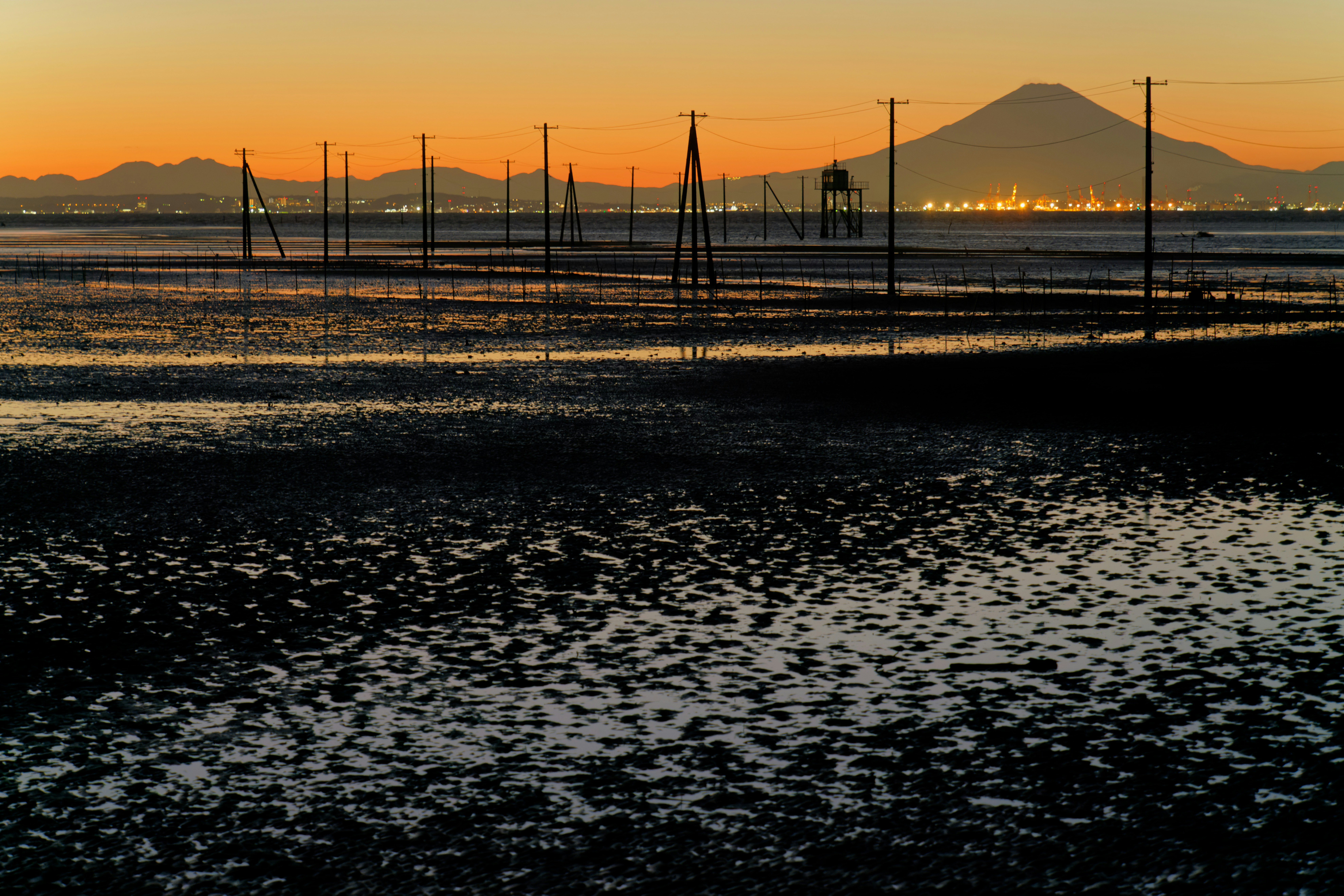 the sun is setting over a beach with a mountain in the background