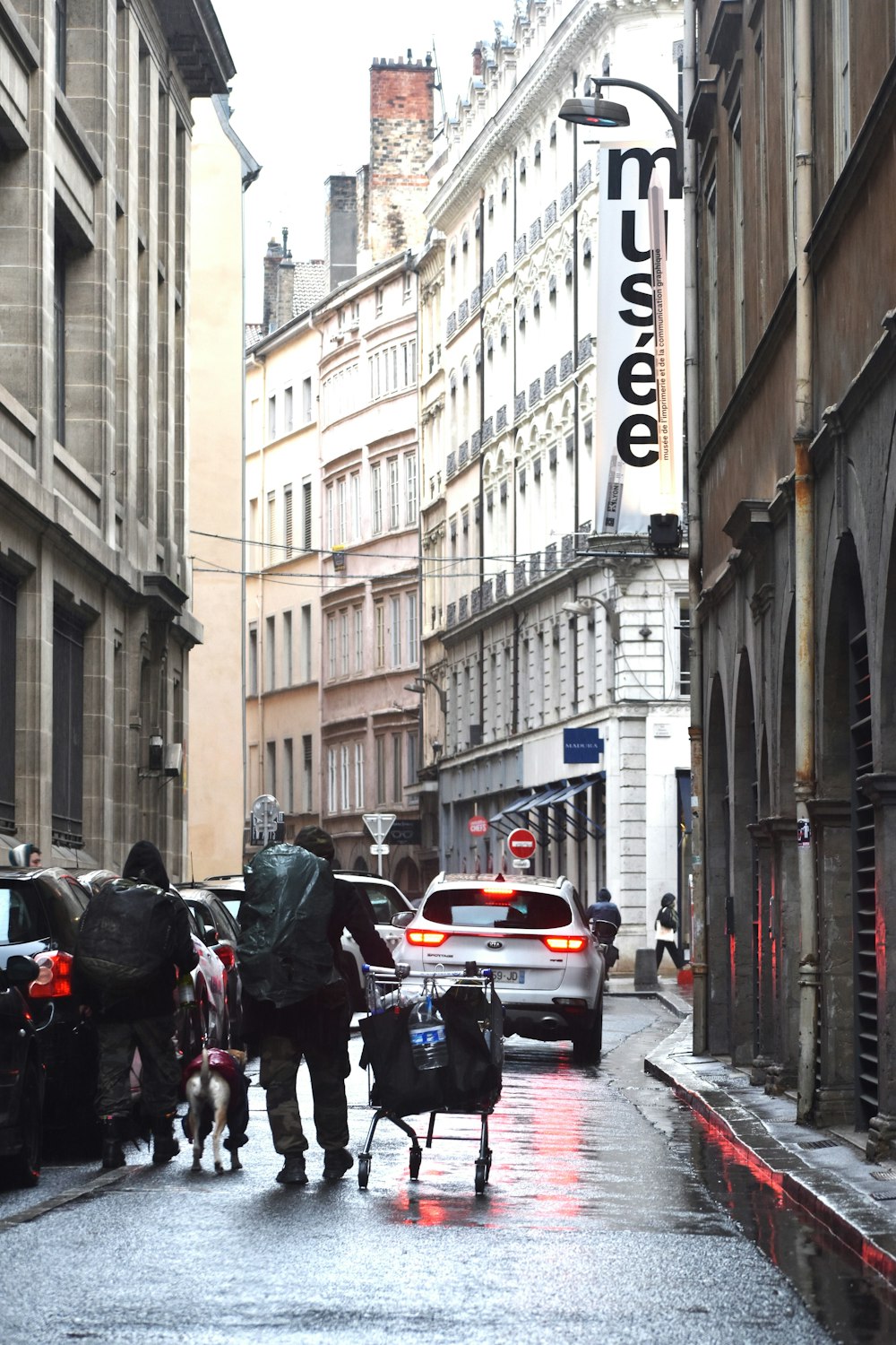 a group of people walking down a street next to tall buildings