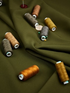 a group of spools of thread sitting on top of a green cloth
