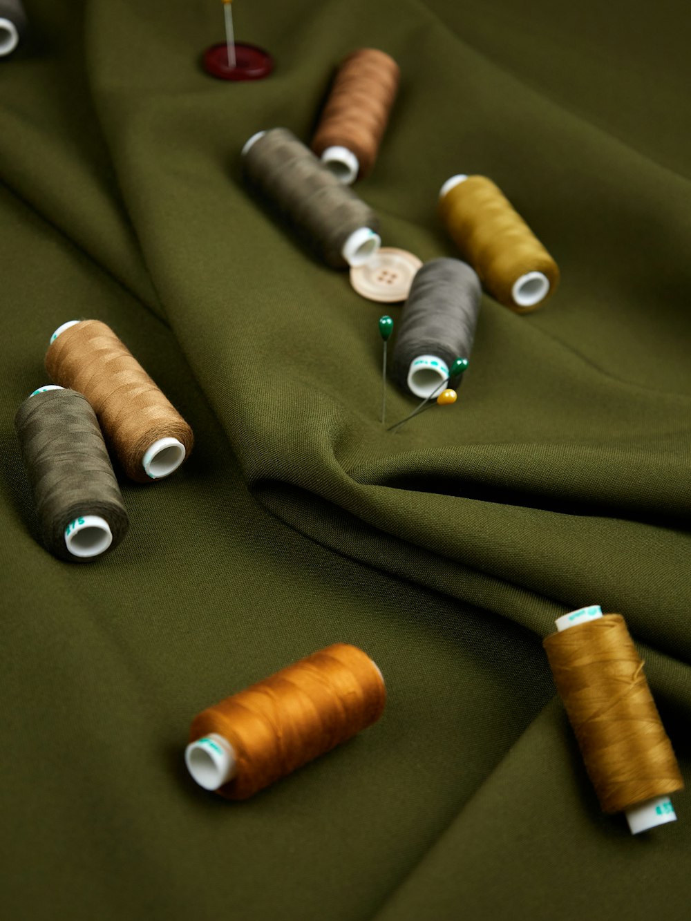 a group of spools of thread sitting on top of a green cloth