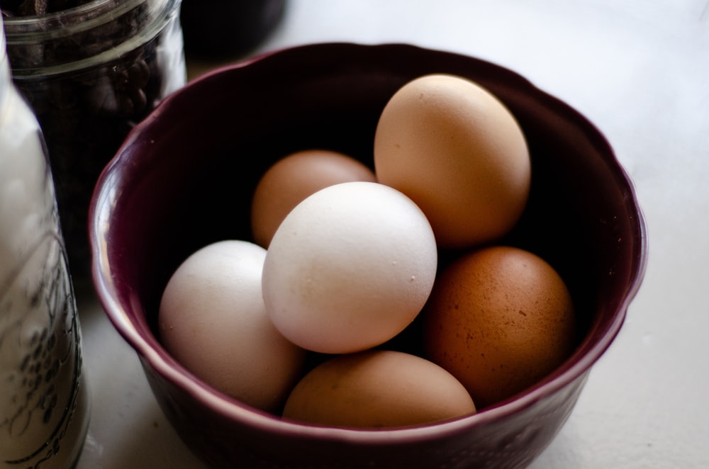 a purple bowl filled with brown and white eggs