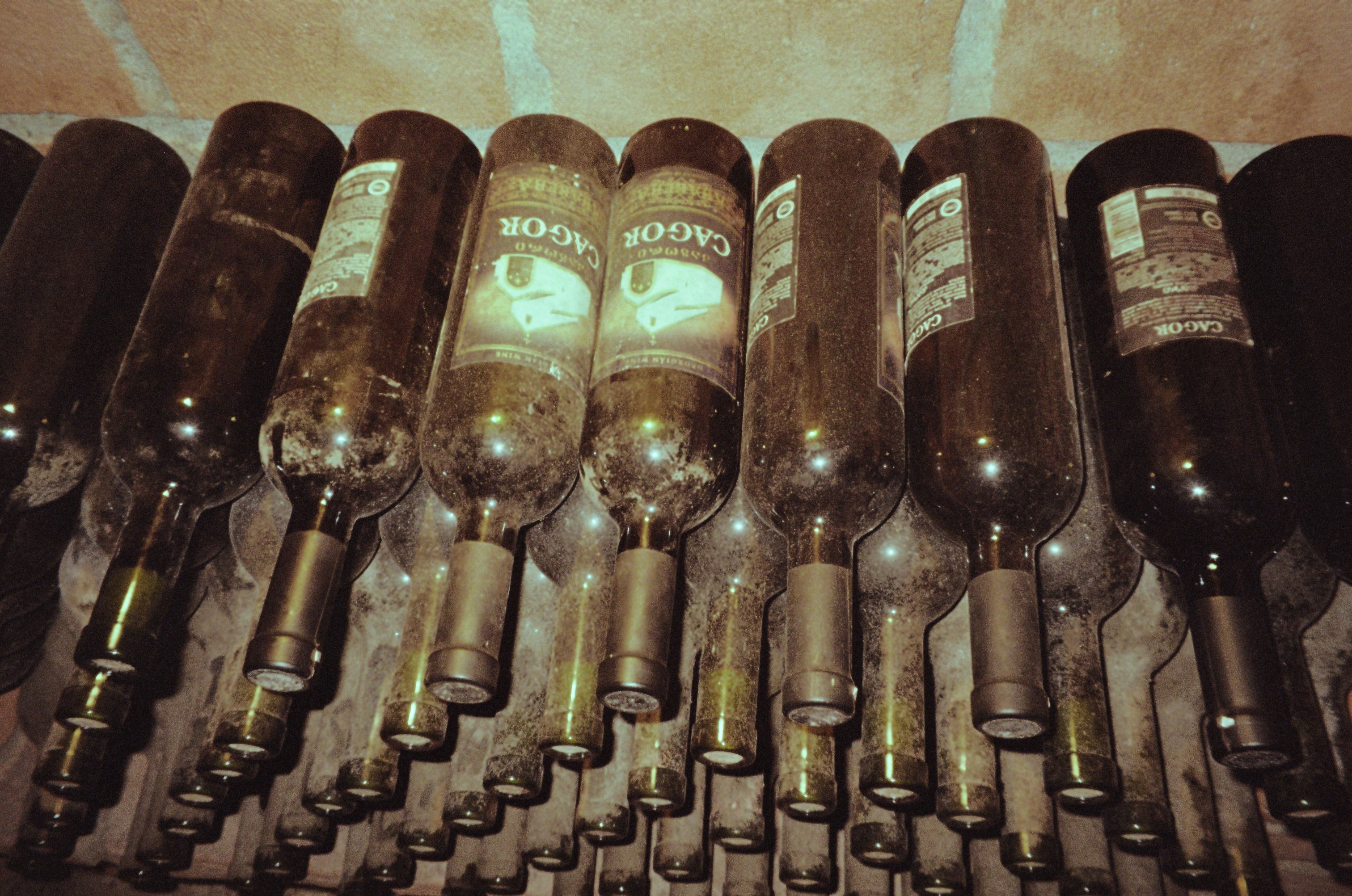 a bunch of wine bottles lined up in a row, 
