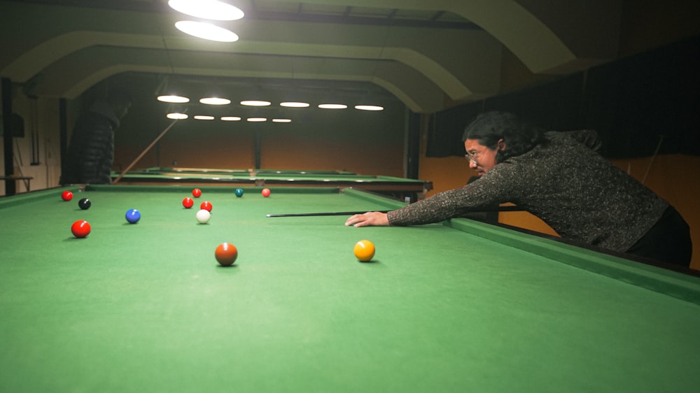 a man is leaning over a pool table