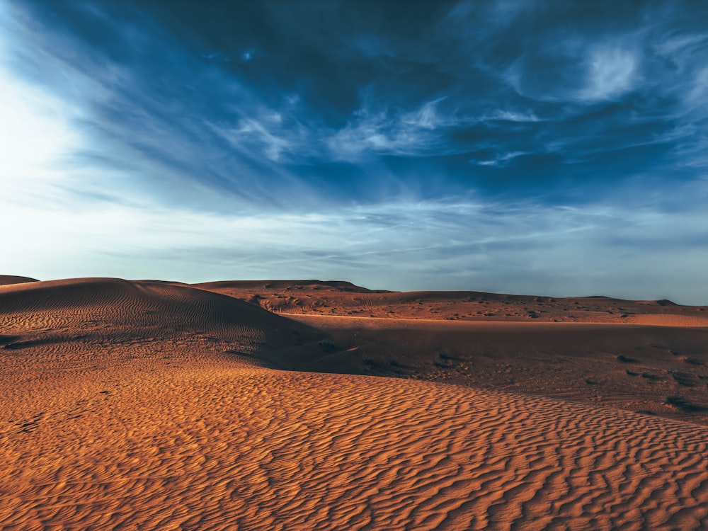 a desert landscape with a blue sky and clouds