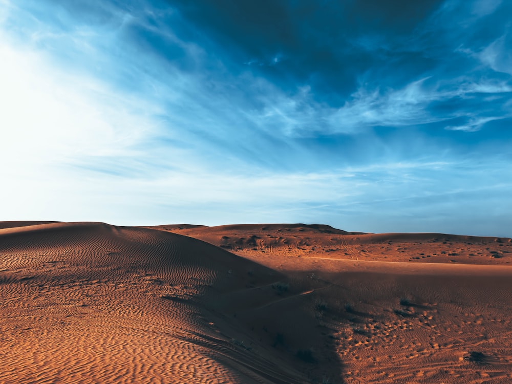 a blue sky and some clouds over a desert