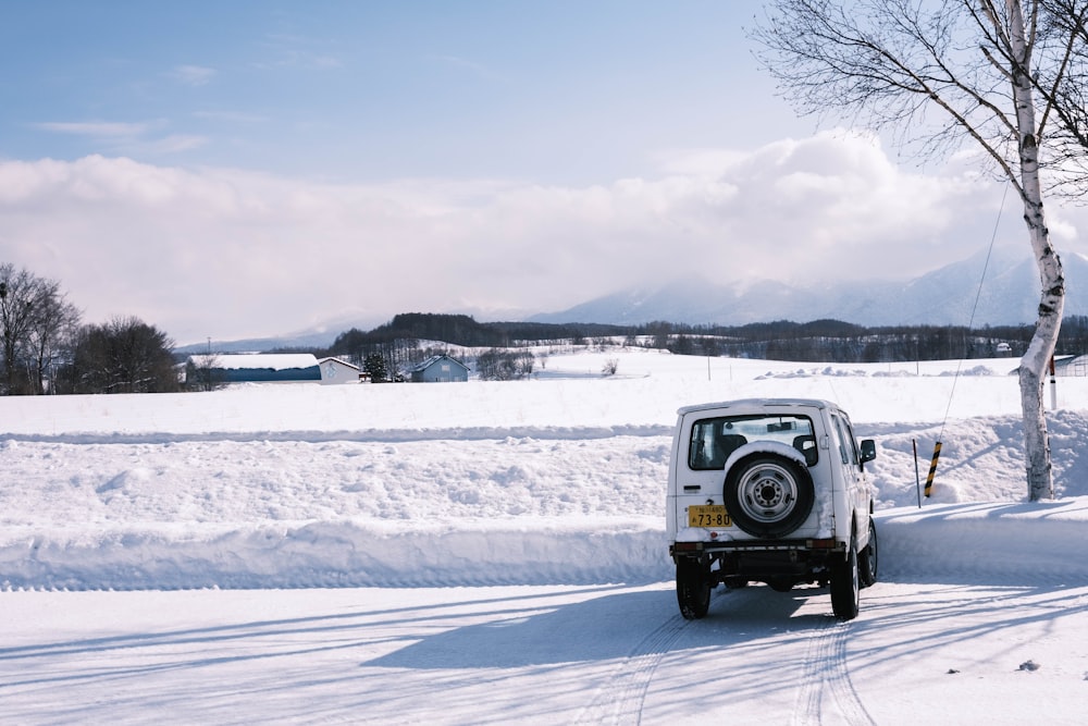 a small white truck driving down a snow covered road