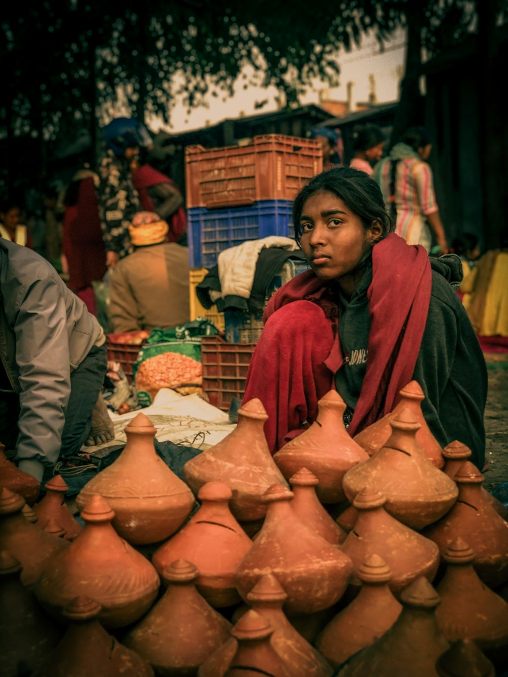 a woman sitting in front of a pile of clay pots
