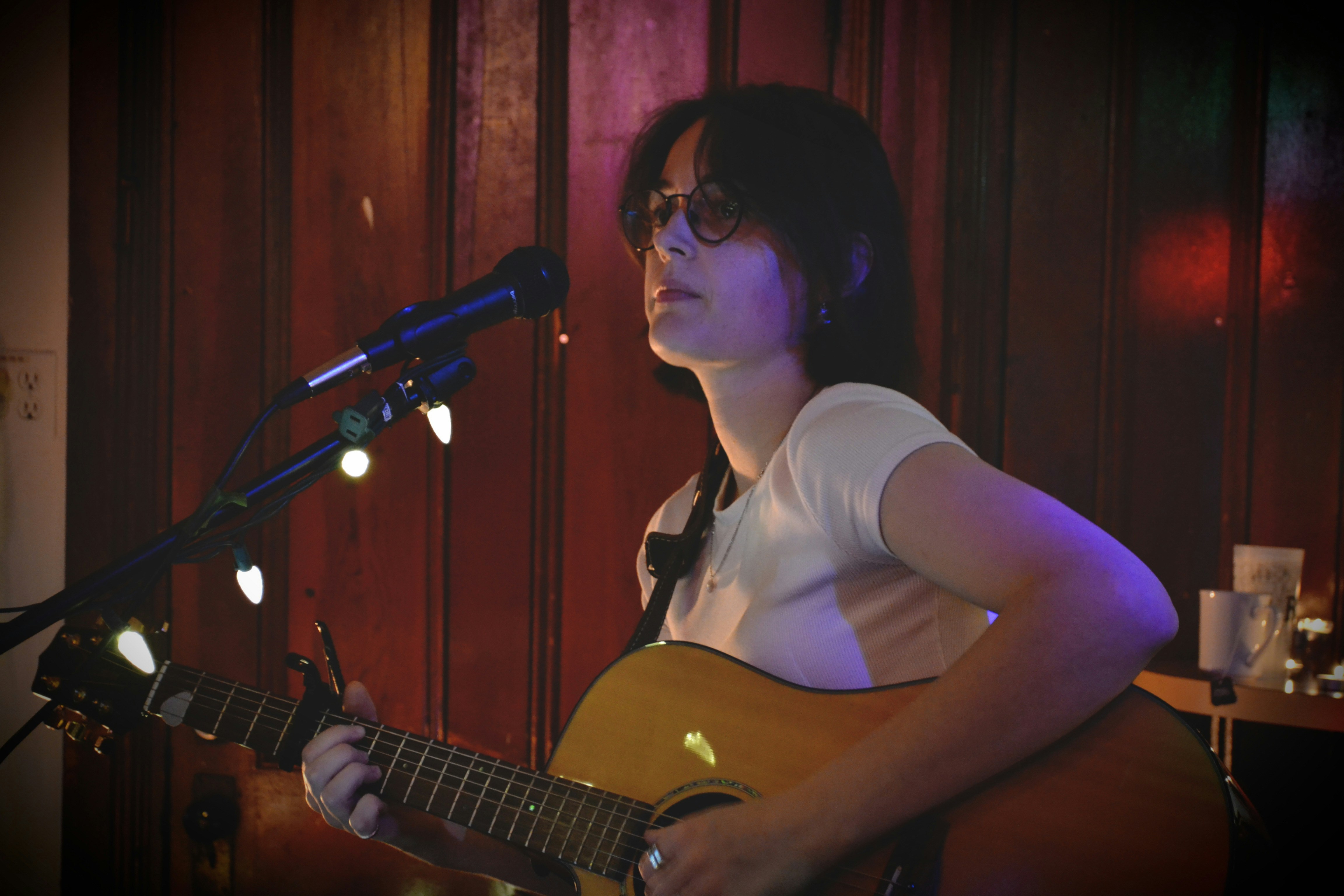 a woman playing a guitar in front of a microphone
