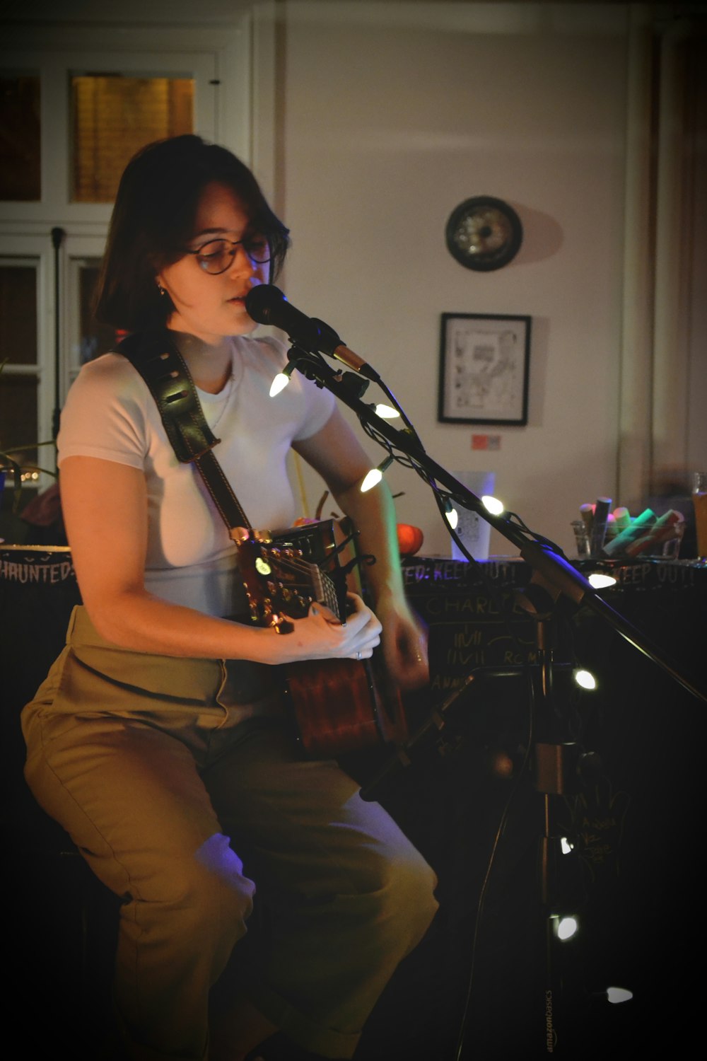 a woman playing a guitar and singing into a microphone