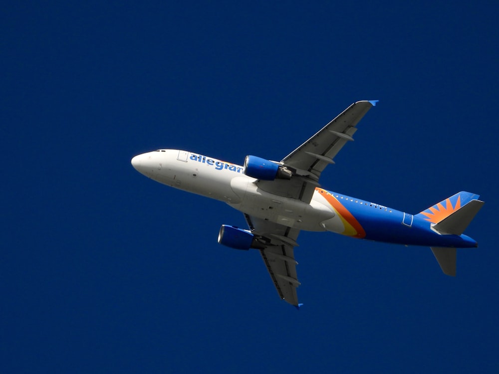 a blue and white airplane flying in a blue sky