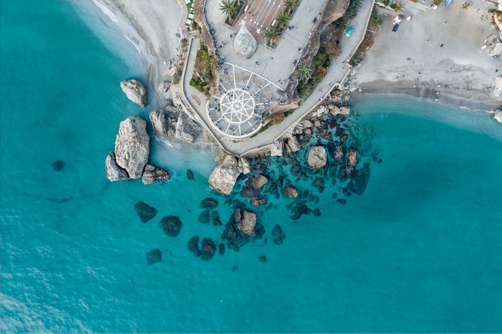 an aerial view of a beach with rocks and a gazebo