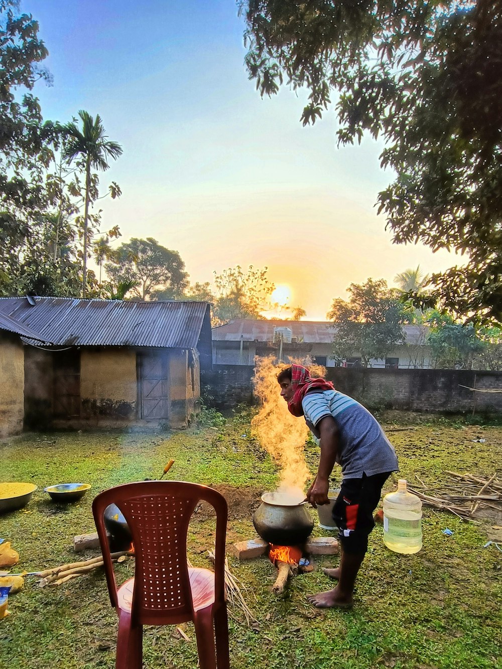 a man standing over a pot on top of a fire