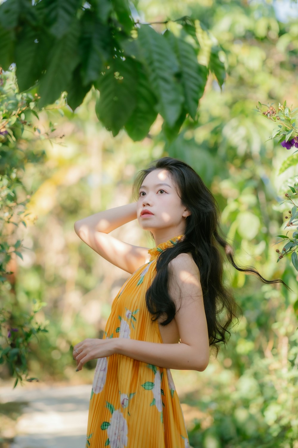 a woman in a yellow dress standing under a tree