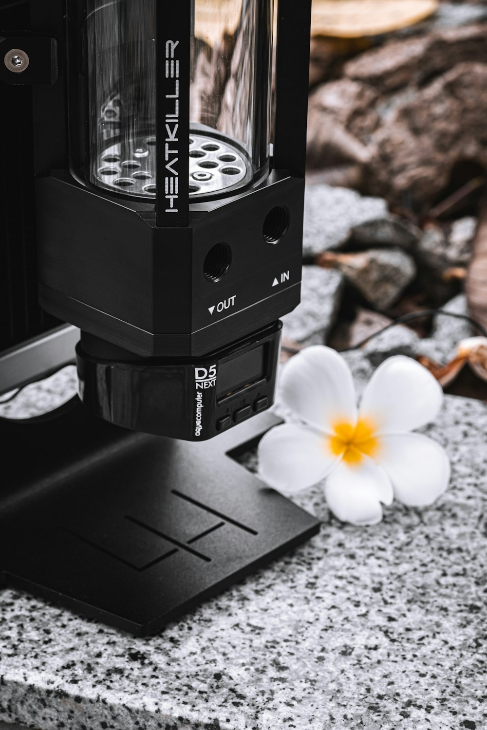 a coffee maker sitting on top of a counter next to a flower
