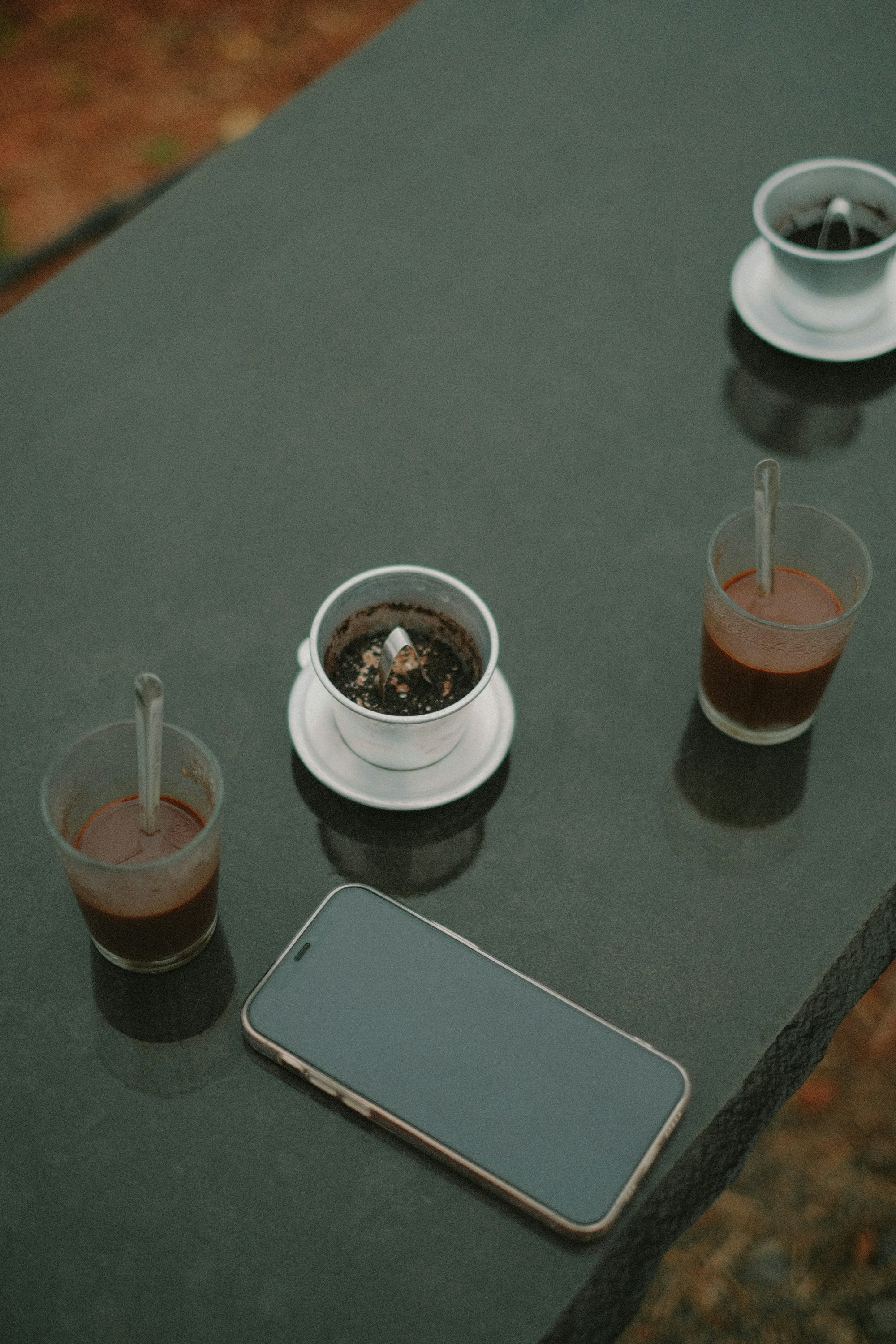 a table topped with two cups of coffee and a cell phone