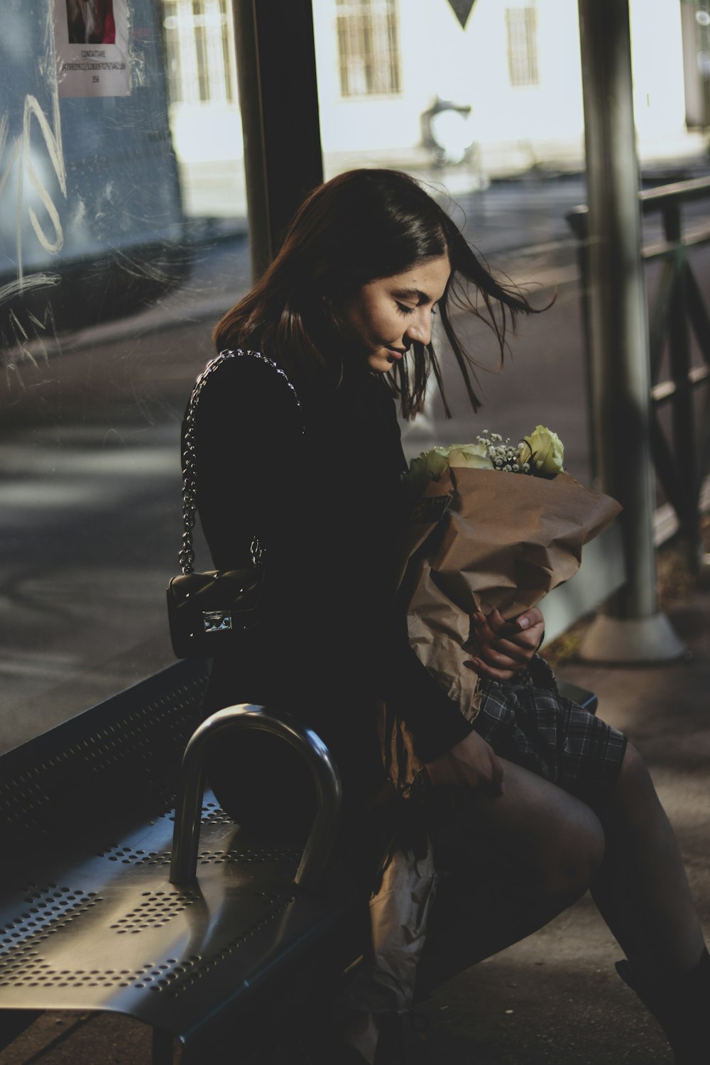 a woman sitting on a bench with a sandwich in her hand