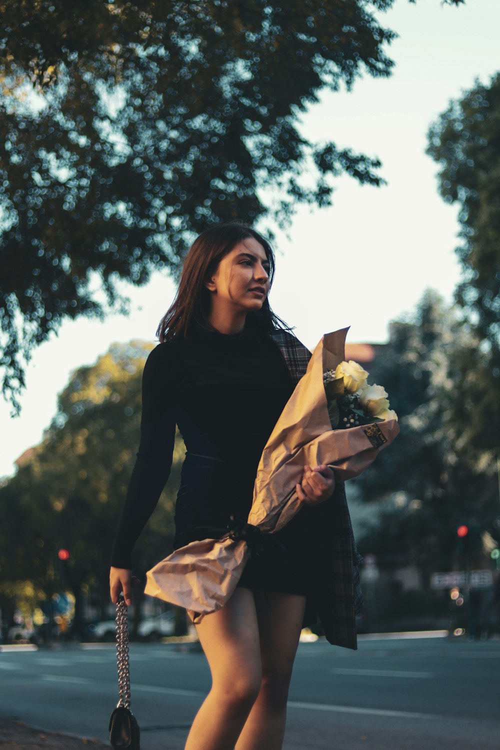 a woman walking down a street holding a bouquet of flowers