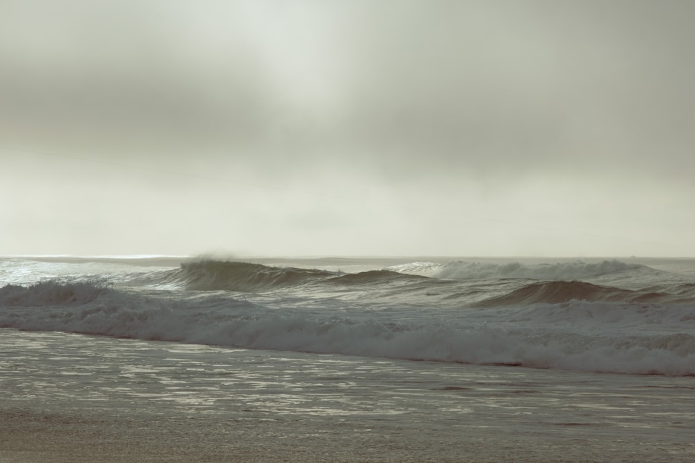 una persona in piedi su una spiaggia con una tavola da surf