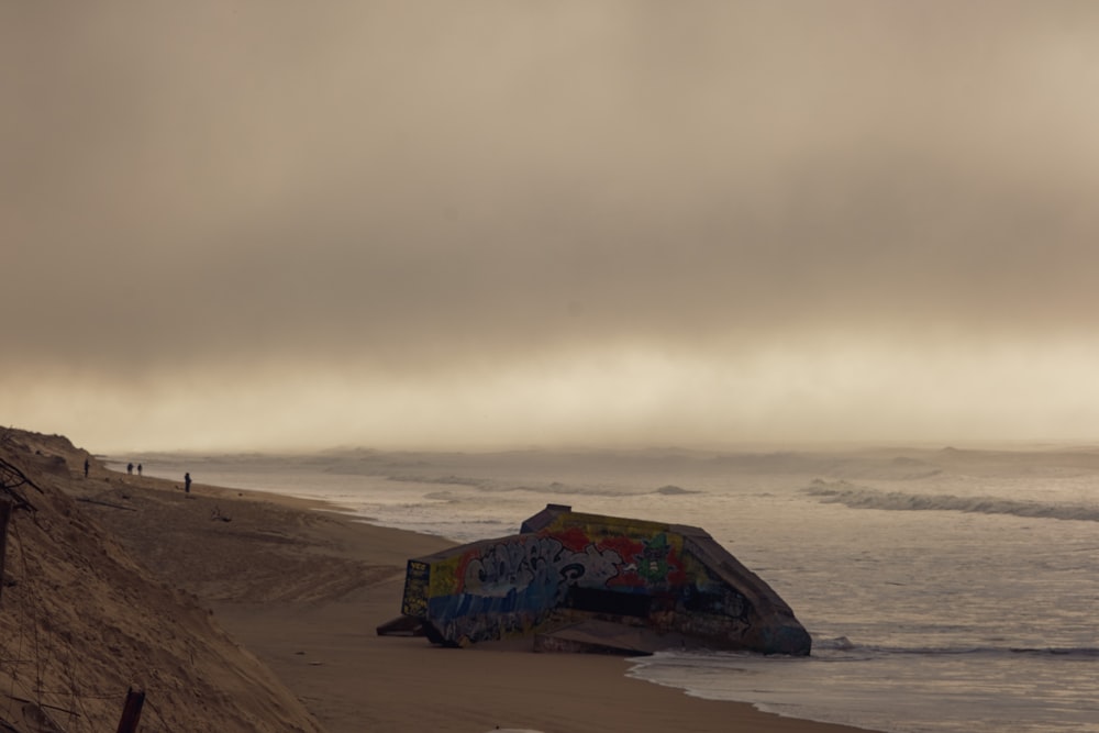 a sandy beach covered in graffiti next to the ocean