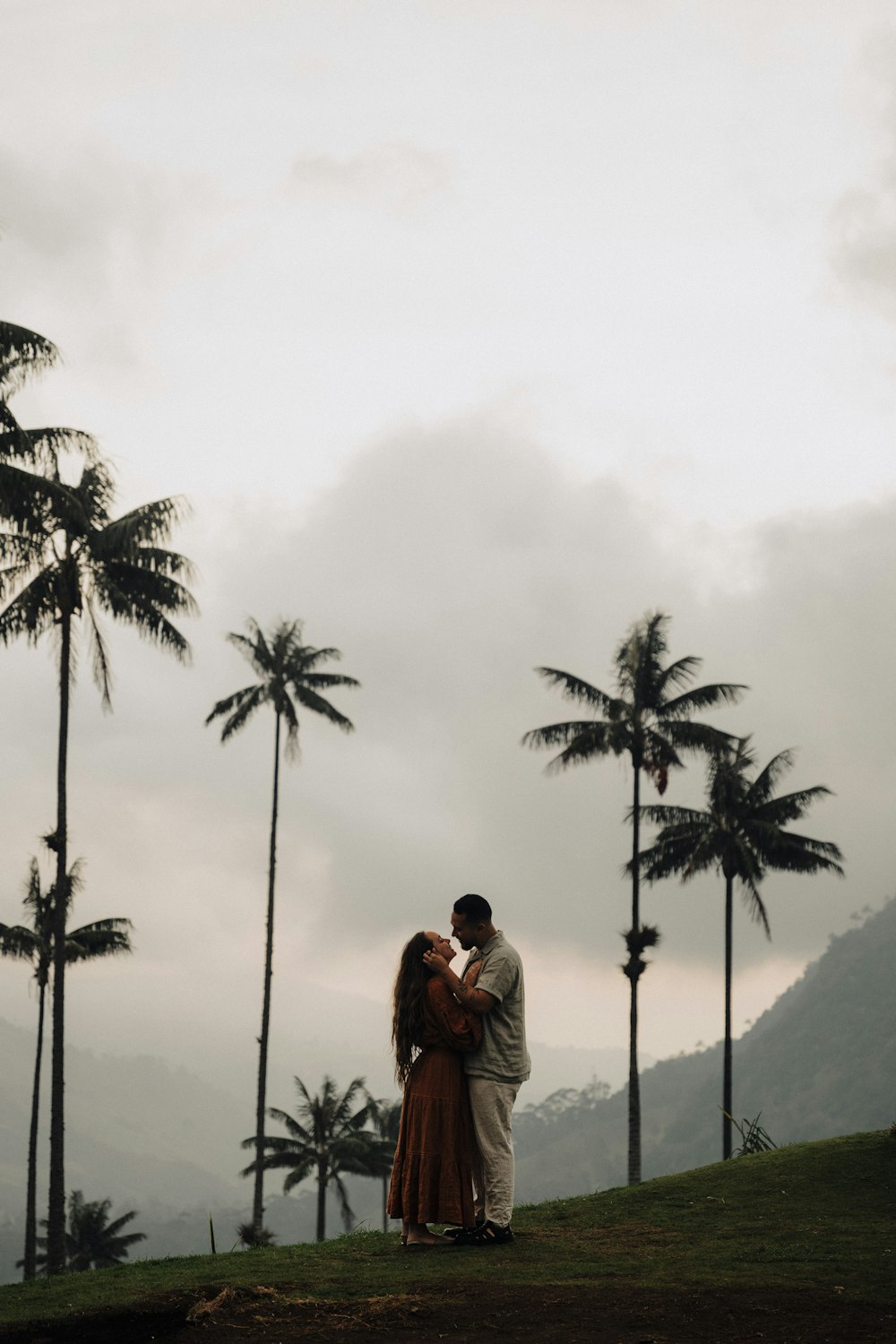 a man and woman standing in front of palm trees