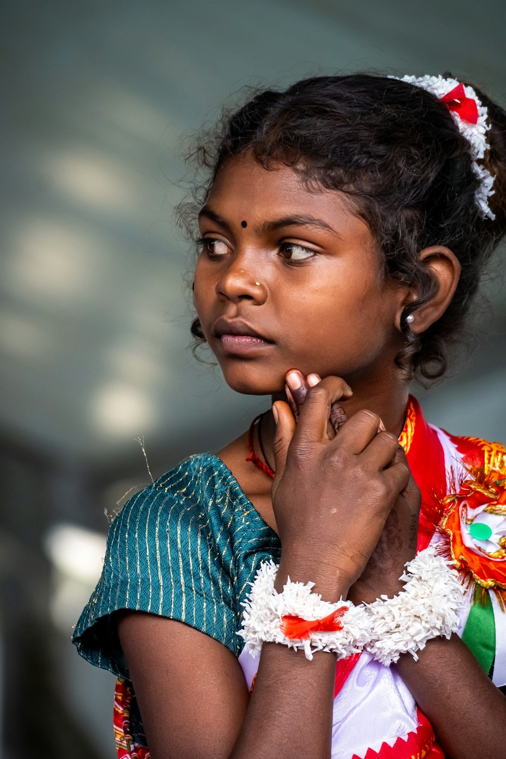 a young girl in a colorful dress is holding her hands together