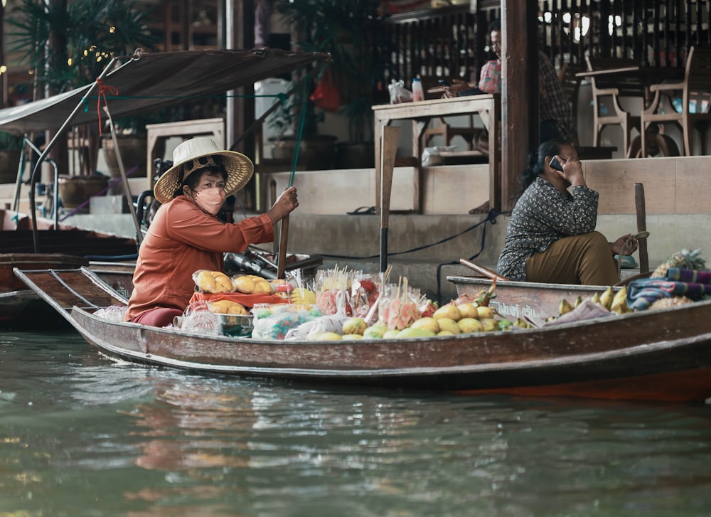 uma mulher sentada em um barco cheio de frutas