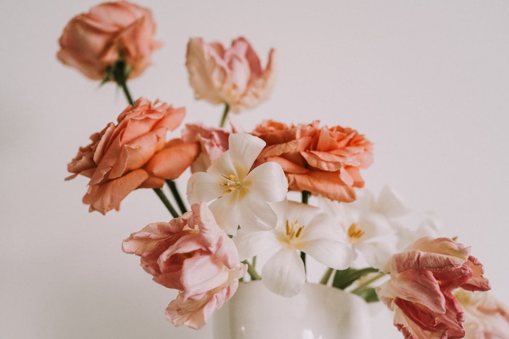 a white vase filled with pink and white flowers