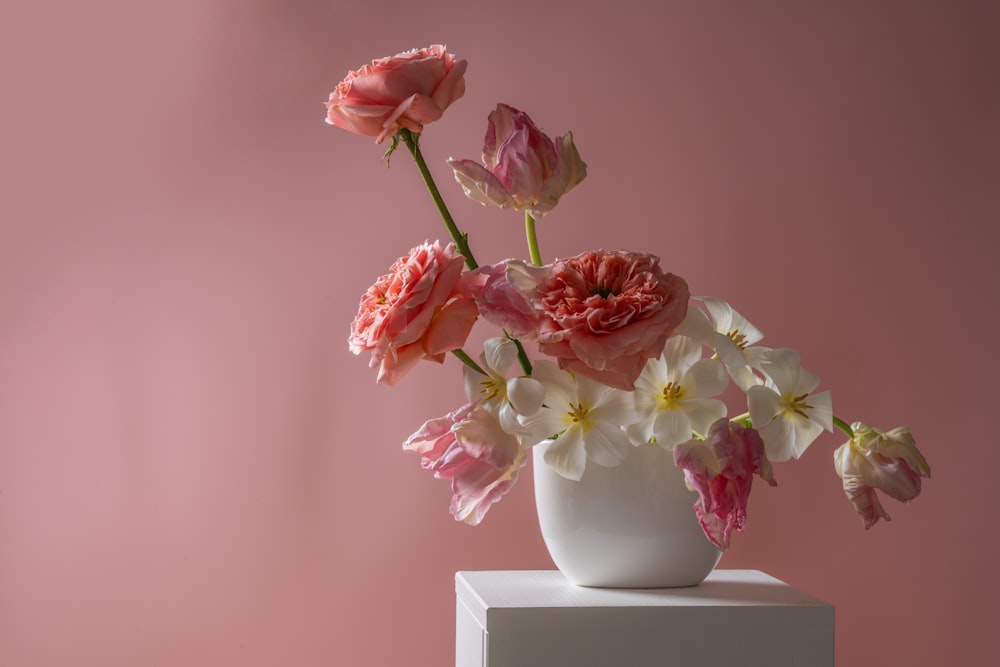 a white vase filled with pink and white flowers