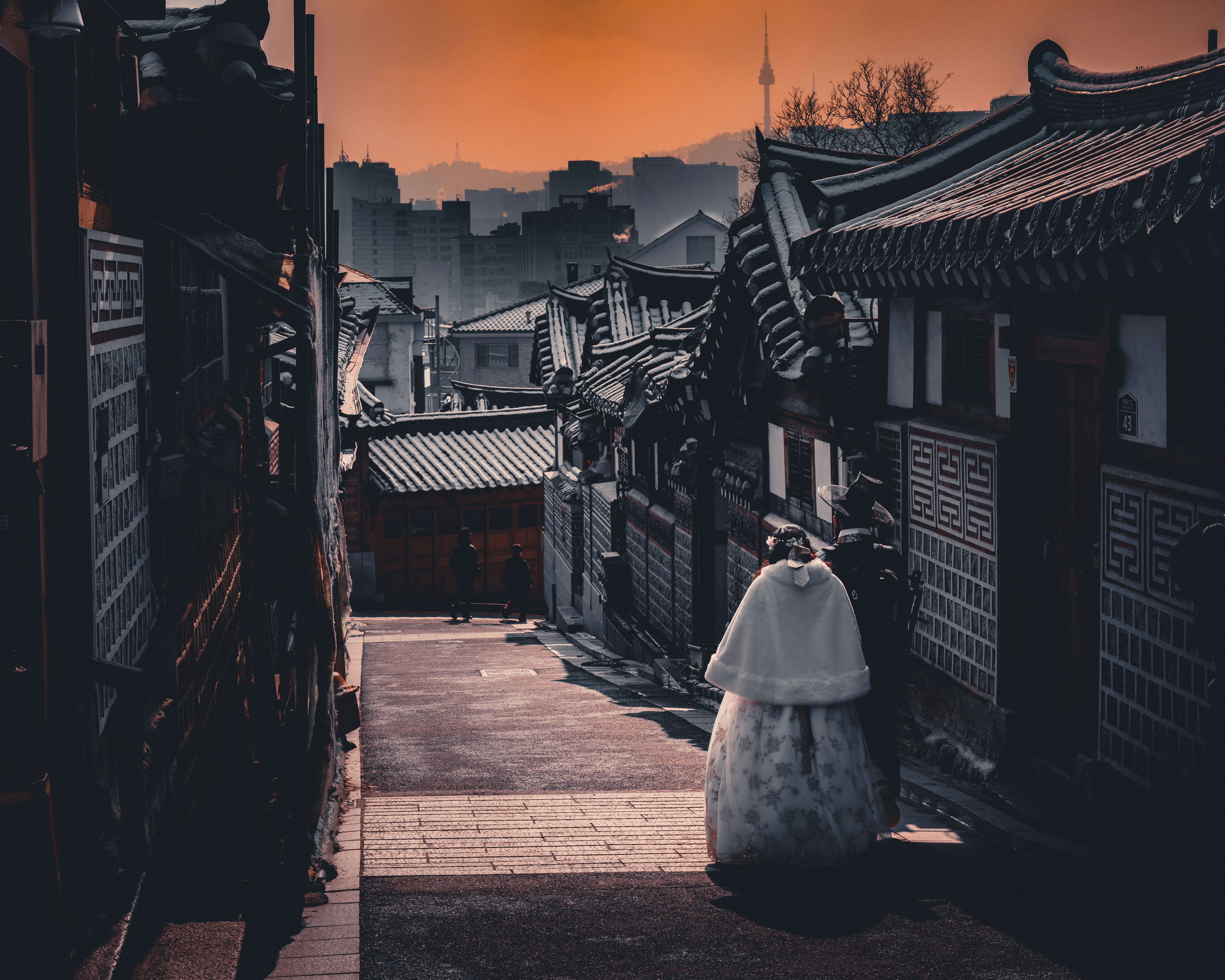 a woman in a white dress walking down a street