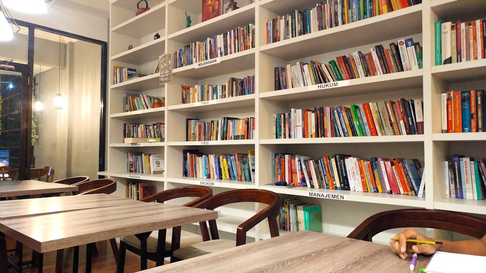 a library filled with lots of books next to wooden tables