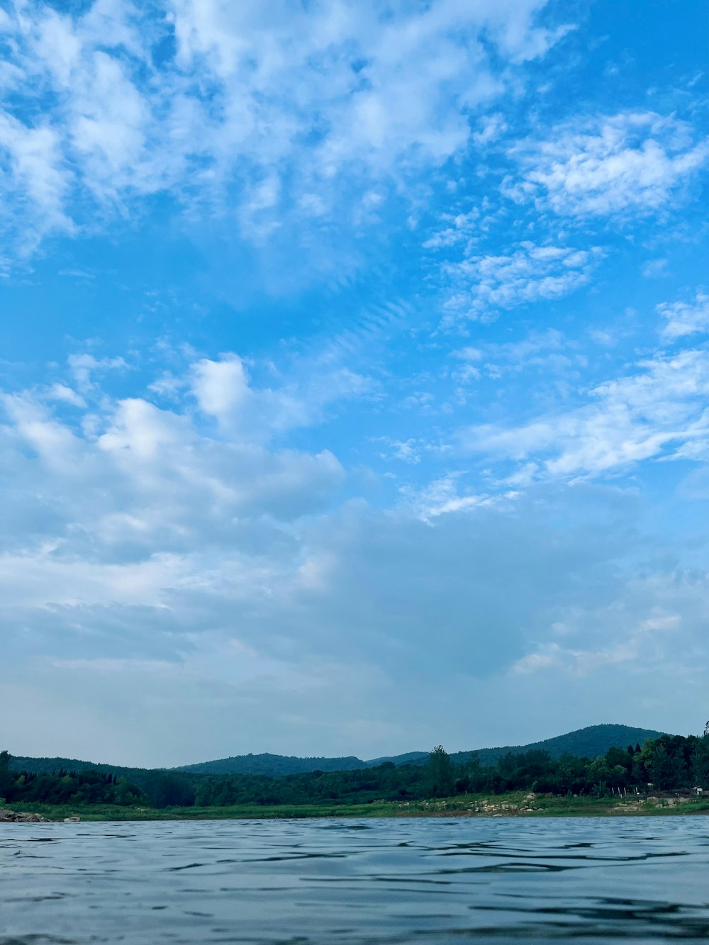 a boat floating on top of a lake under a cloudy blue sky