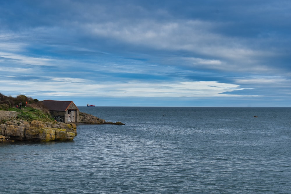 a house sitting on the edge of a cliff next to the ocean